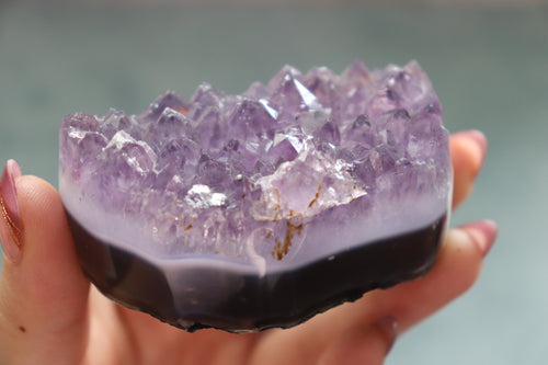 Amethyst crystal bowl held in a hand against a blurred background
