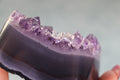 Amethyst On a Agate base crystal  held by a hand against a neutral background