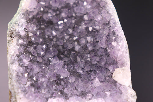 Close-up of a purple amethyst crystal formation on a dark background