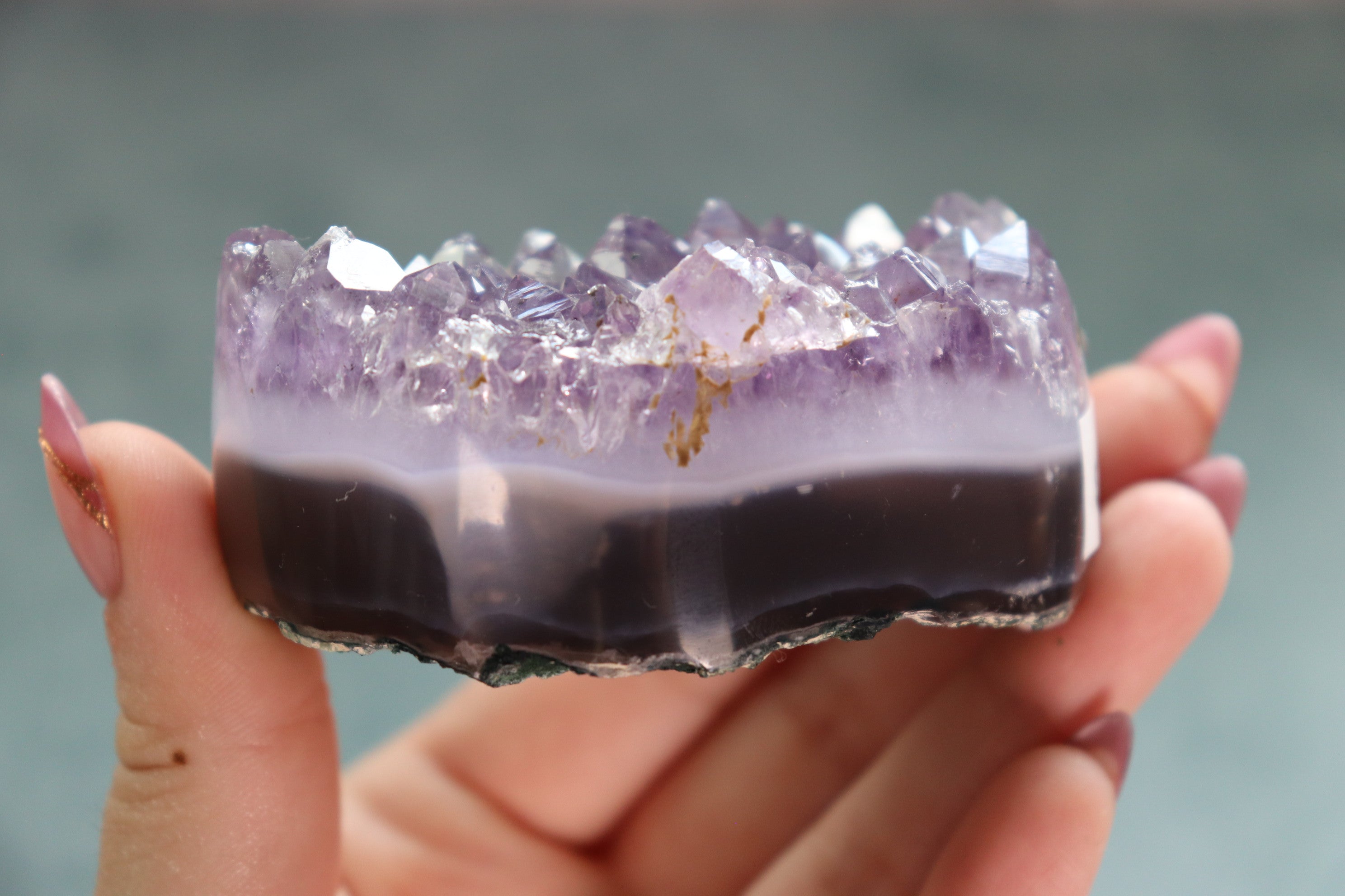 Amethyst crystal held in a hand against a blurred background