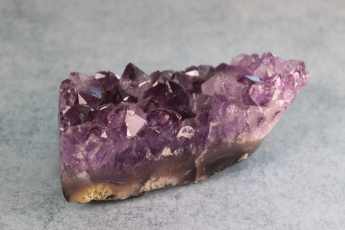 Amethyst crystal cluster on a gray background