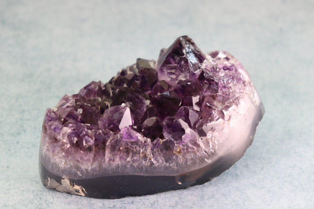 Amethyst crystal cluster on a light gray background