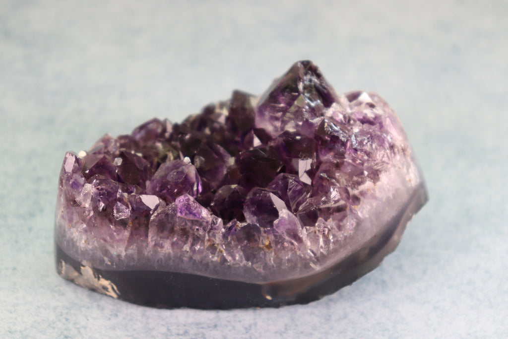 Amethyst crystal cluster on a light gray background