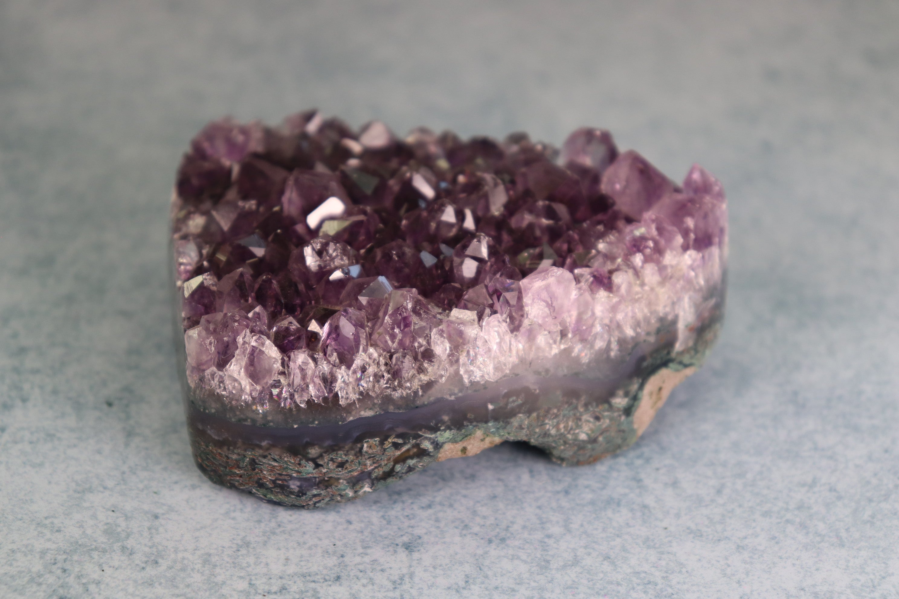 Amethyst with moss agate crystal cluster on a gray background
