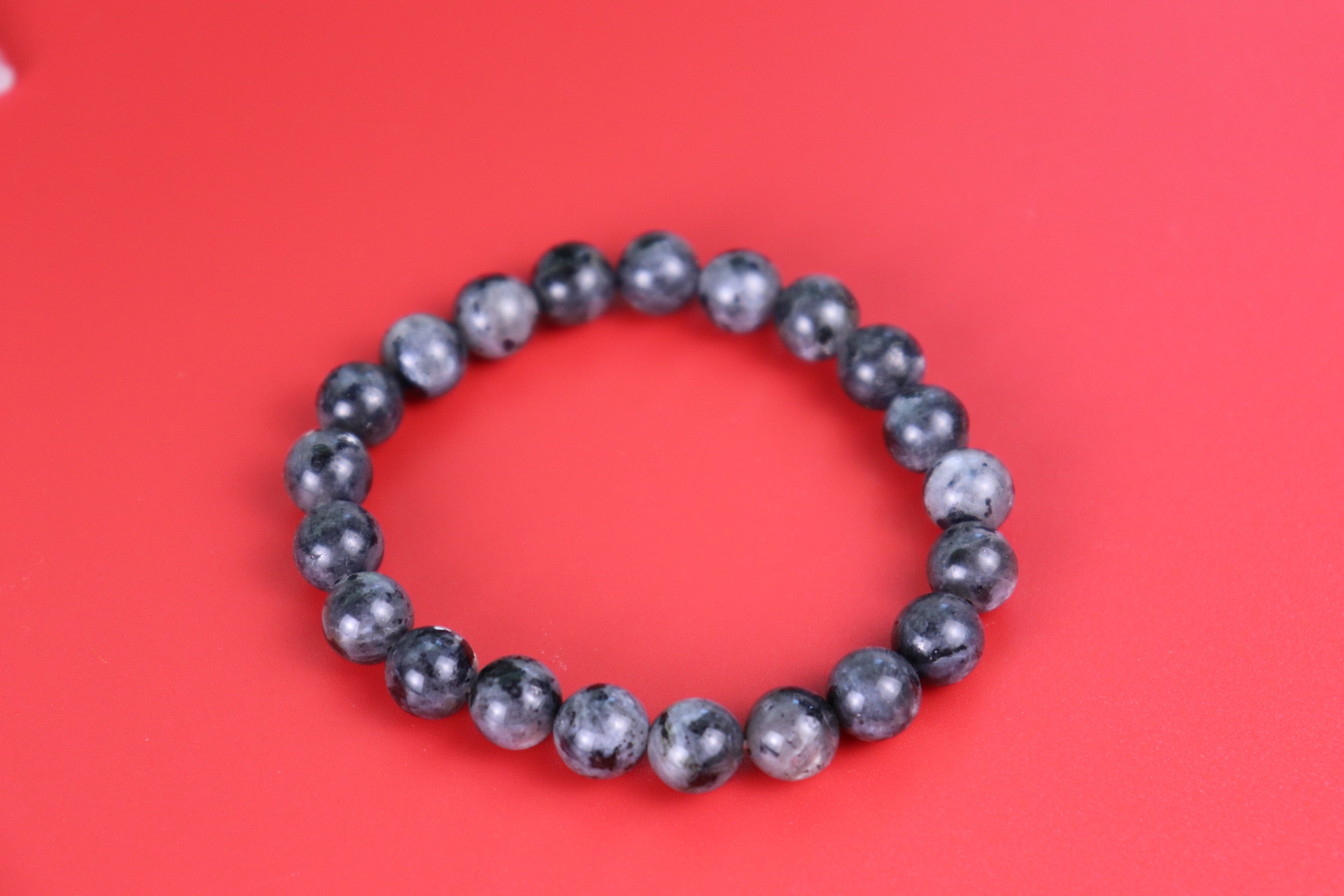 Black beaded Larvikite bracelet on a red background