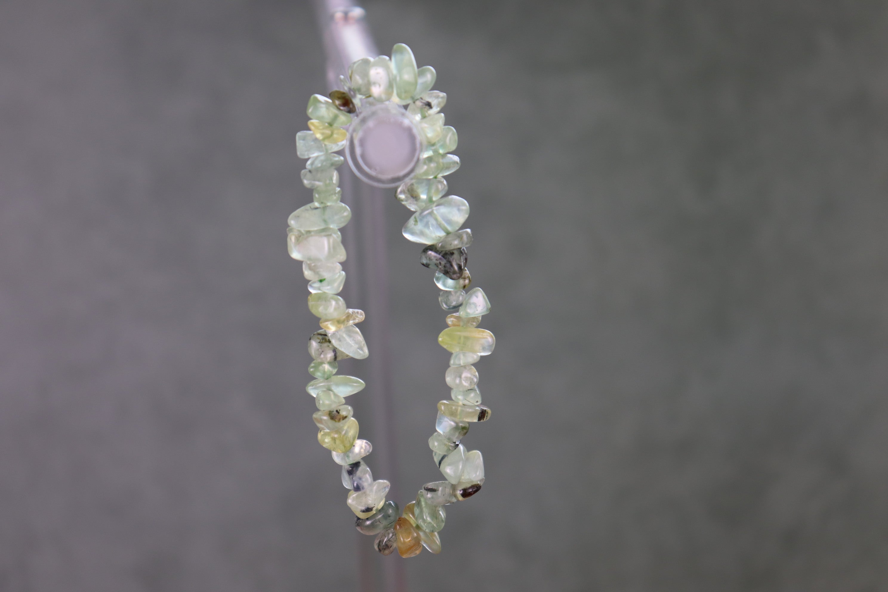 Beaded chip bracelet with multicolored prehnite stones on a gray background
