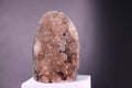 rainbow amethyst  crystal rock on a white pedestal against a gray background