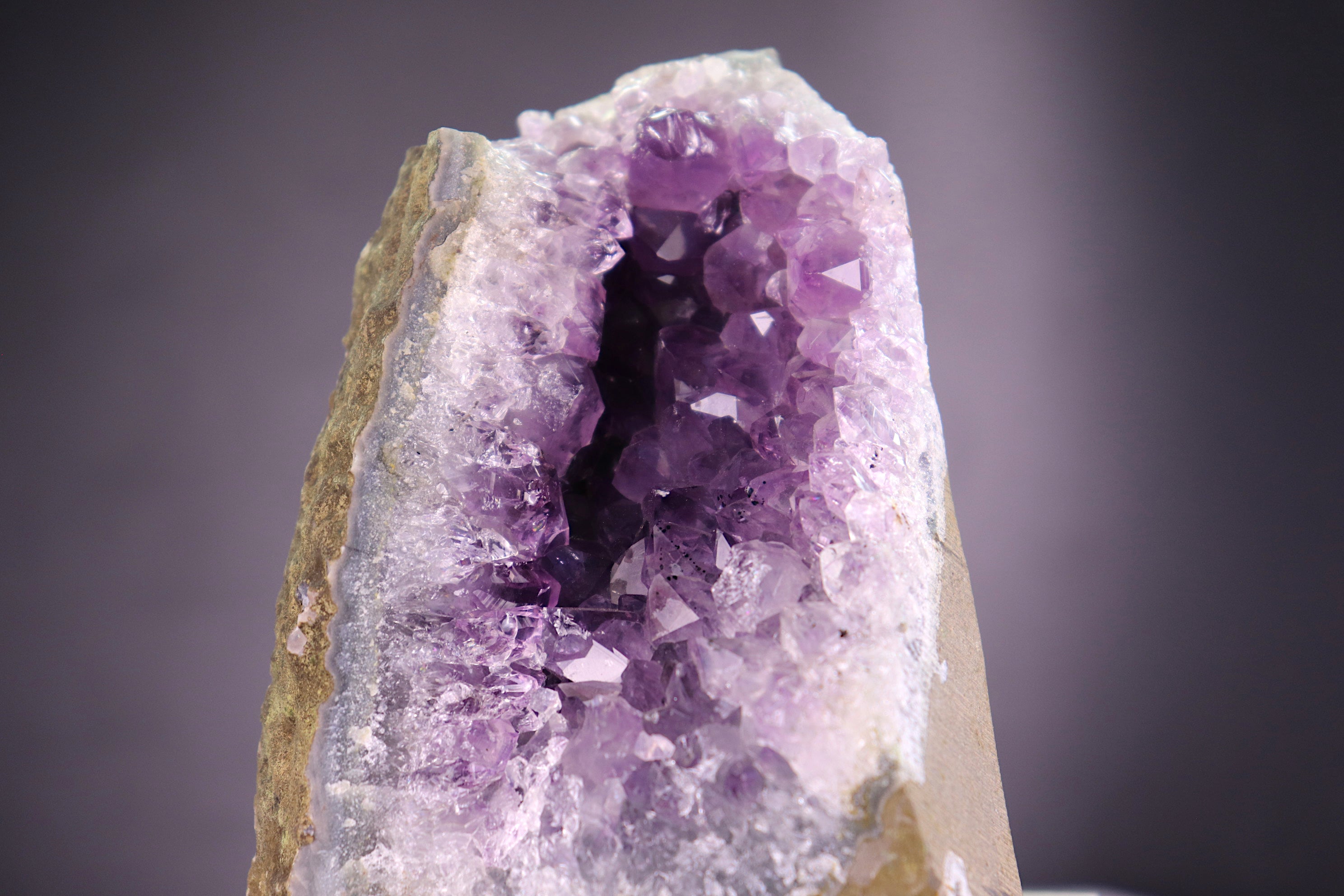 Amethyst crystal with a dark center on a gray background