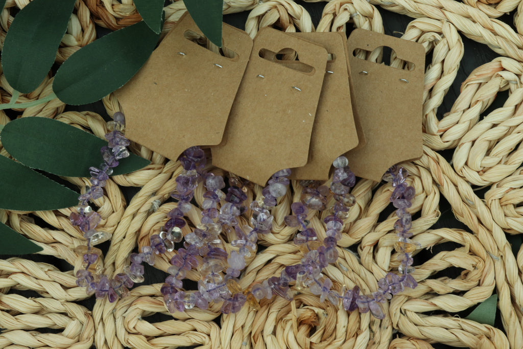 Ametrine bracelet with brown earring cards on a woven surface