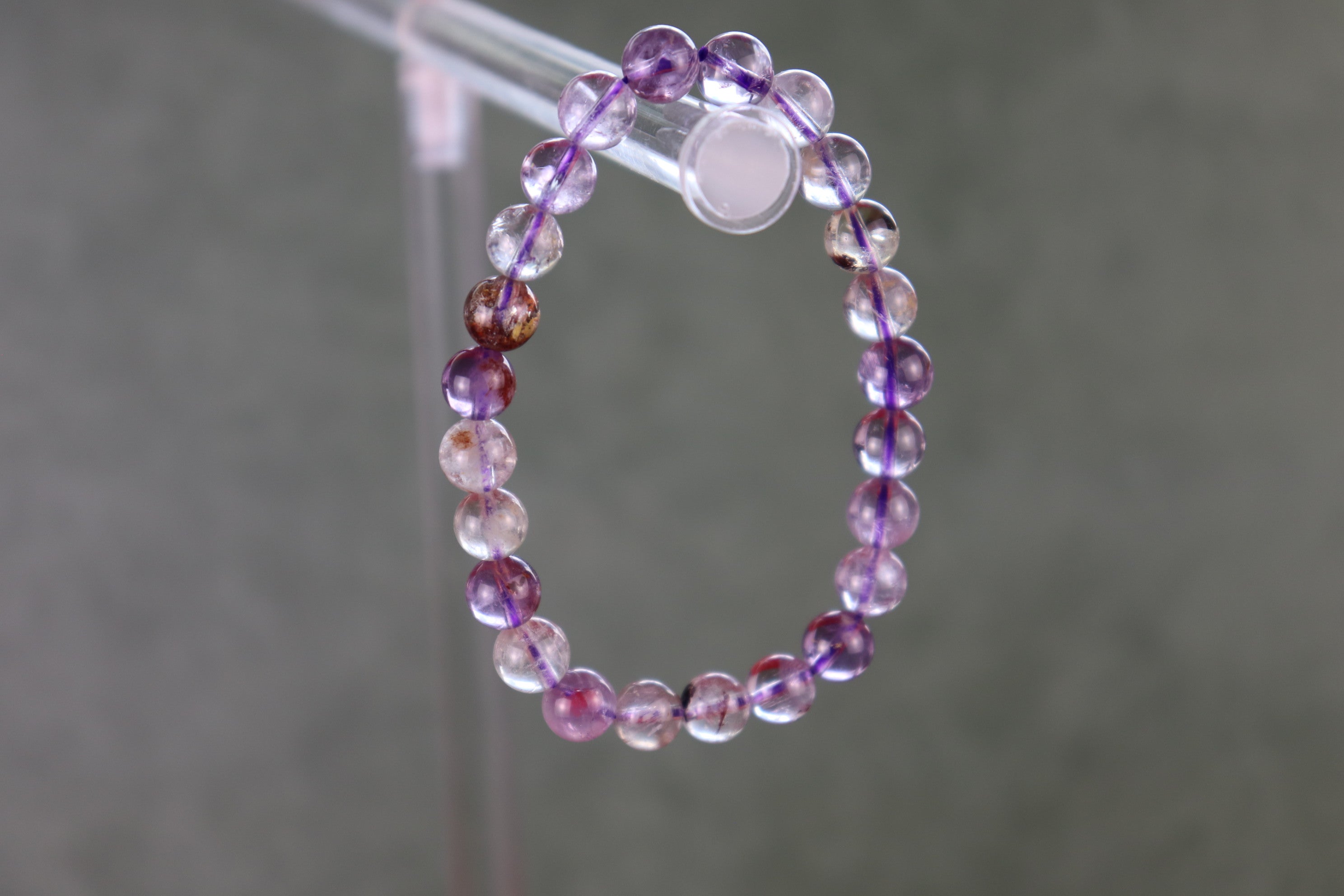 Auralite 23 beaded bracelet on a clear stand against a gray background