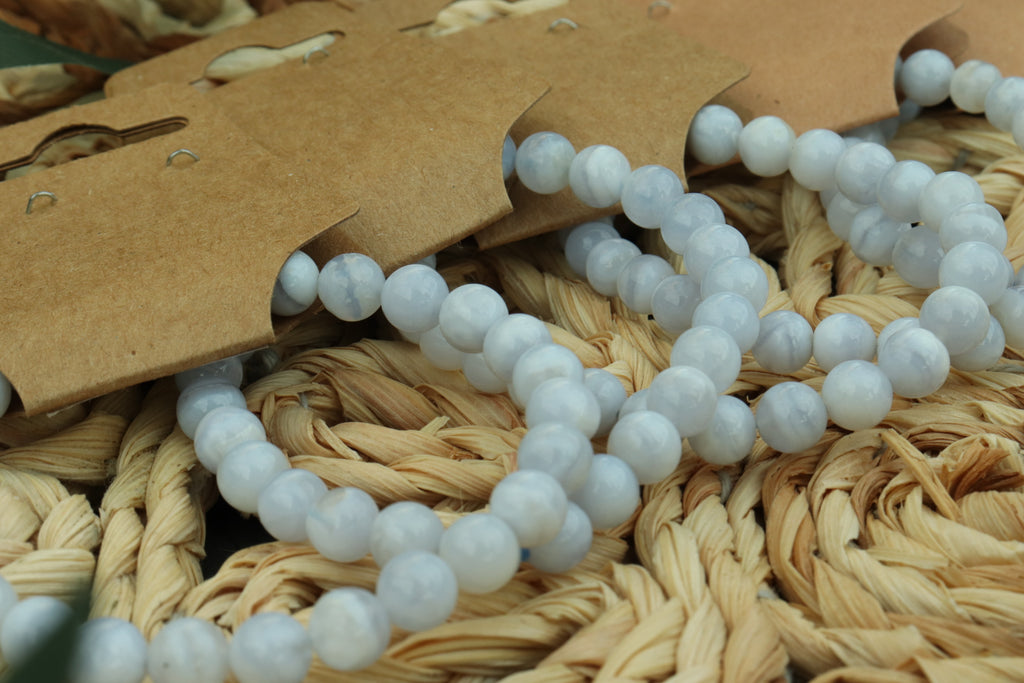 blue lace agate beaded bracelet  on a woven surface with a brown tag
