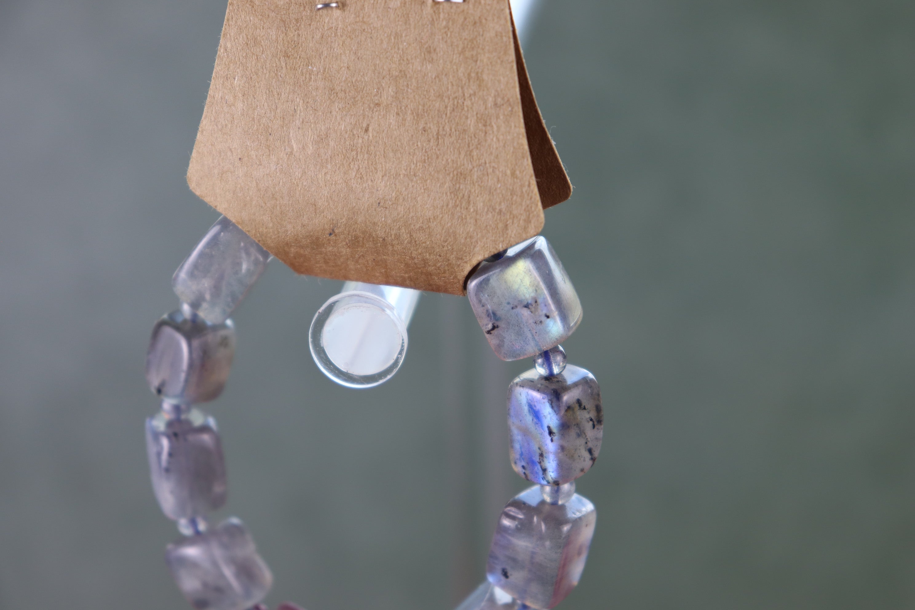 Labradorite bracelet on a clear stand against a blurred background