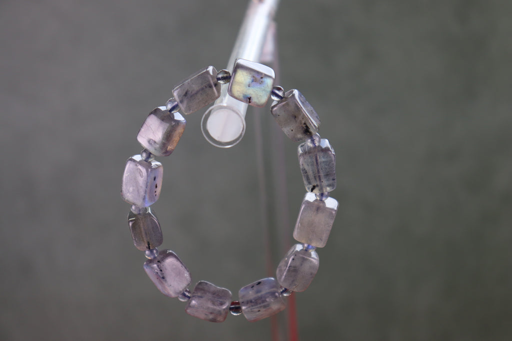 Labradorite bracelet with purple and clear beads on a gray background