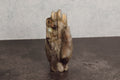 Carved labradorite stone figure of a hand on a dark surface with a gray background