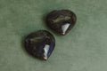 Two heart-shaped labradorite gemstones on a green background