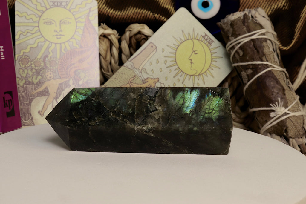Labradorite crystal on a white surface with tarot cards and smudge sticks in the background
