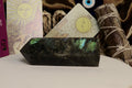 Labradorite crystal on a white surface with tarot cards and smudge sticks in the background