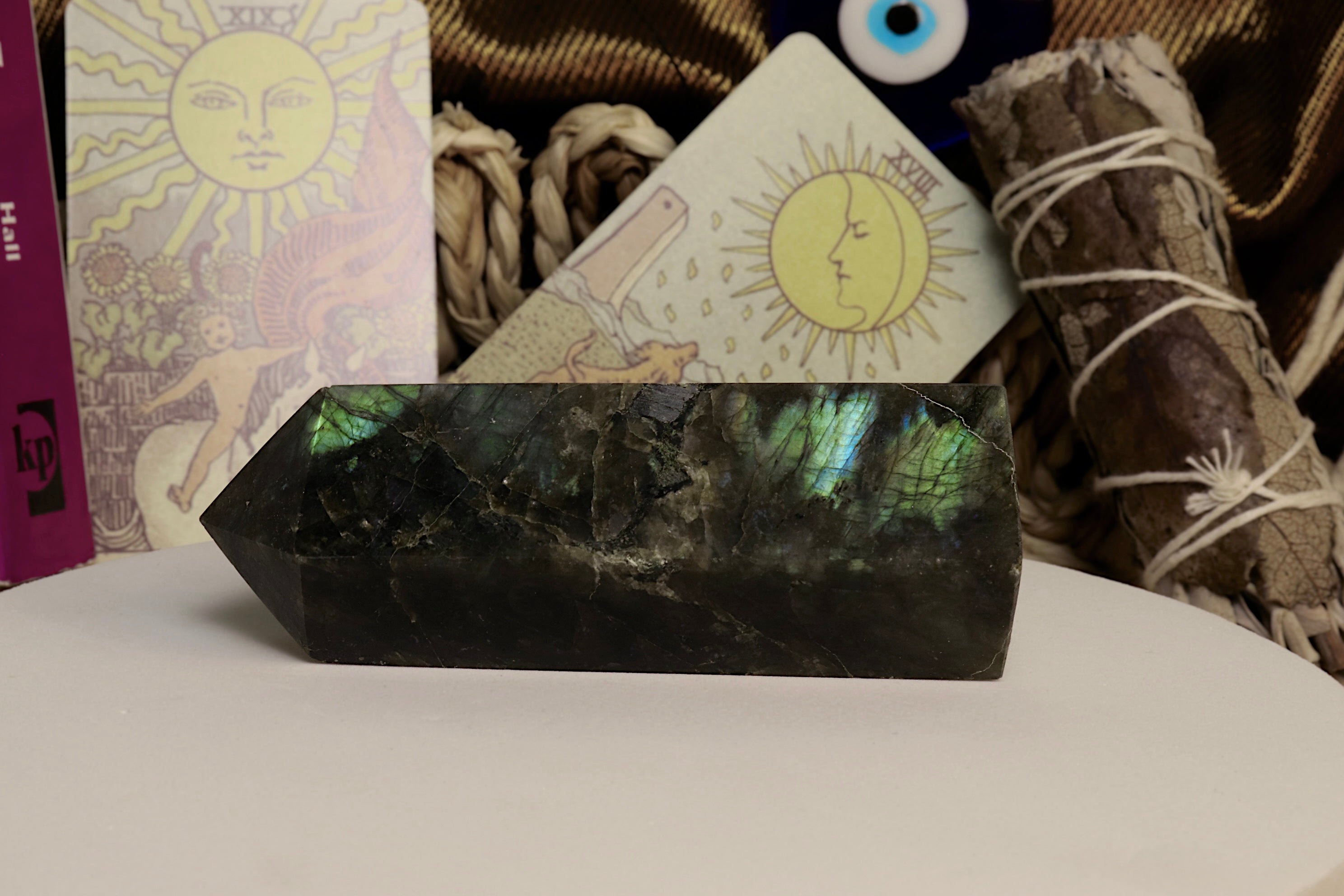 Labradorite crystal on a white surface with tarot cards and smudge sticks in the background