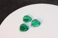 Three green malachite stones on a white surface with a dark background