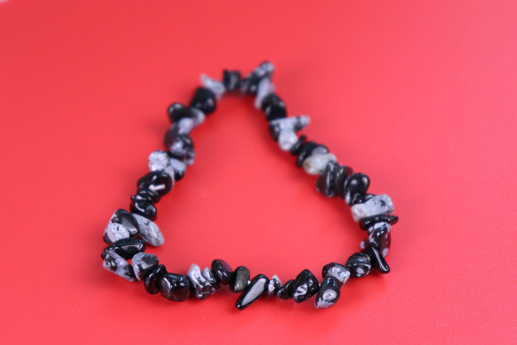 Black and white snowflake obsidian chip beaded bracelet on a red background
