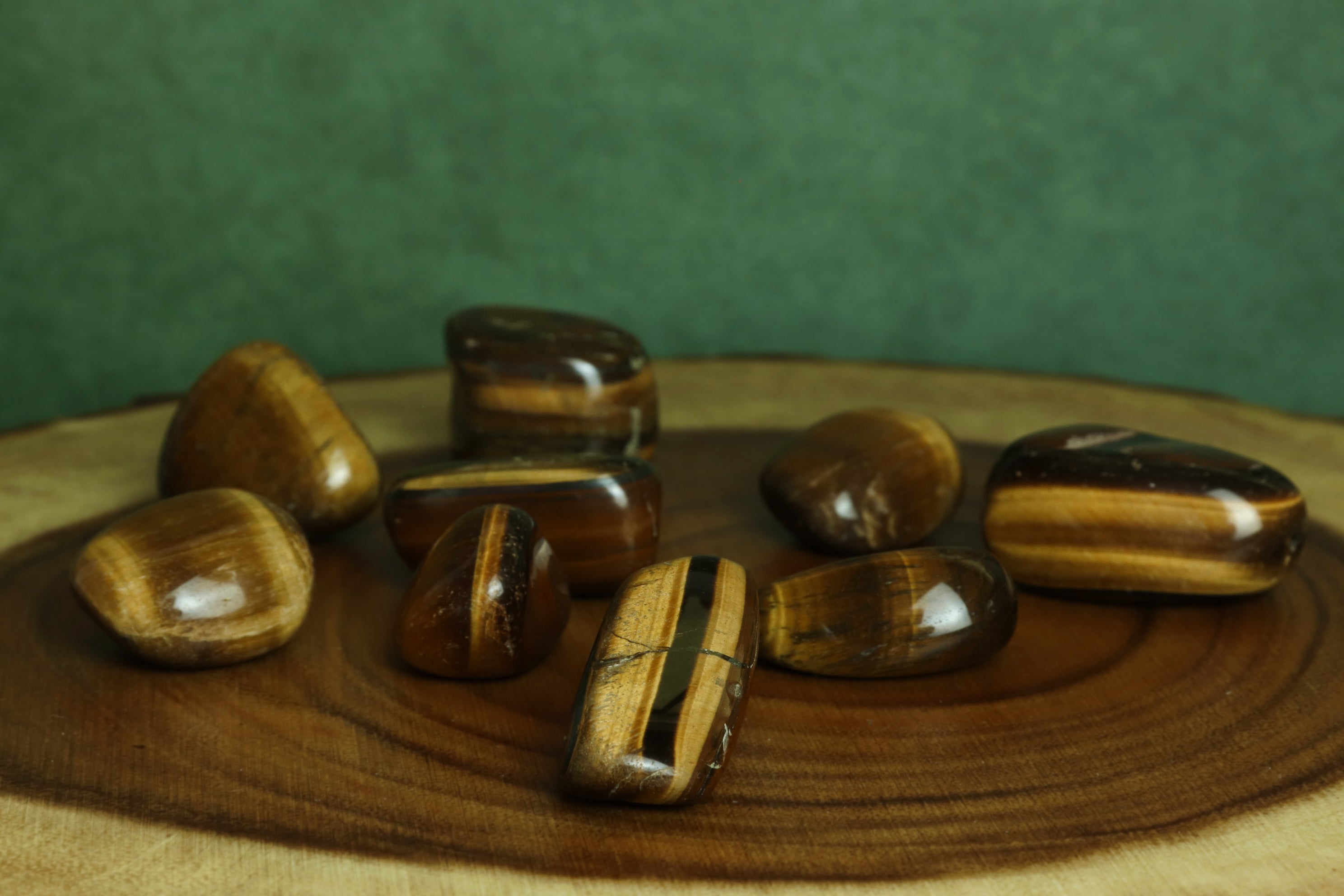Tiger eye stones on a wooden surface with a green background